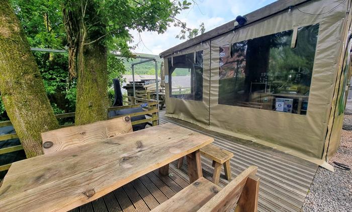 a picnic table sat under a tree next to a wooden building